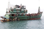 Rohingya and Bangleshi migrants wait on board a fishing boat before being transported to shore, off the coast of Julok