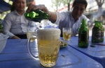 A man pours Saigon beers into a cup at a restaurant in Hanoi, Vietnam