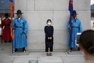 A Chinese tourist wearing a mask to prevent contracting Middle East Respiratory Syndrome (MERS) poses for photographs at the main entrance of the Gyeongbok Palace in central Seoul