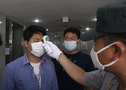 A military official wearing a mask as a precaution against contracting MERS checks the body temperature of a visitor at the entrance of the Defense Ministry in Seoul