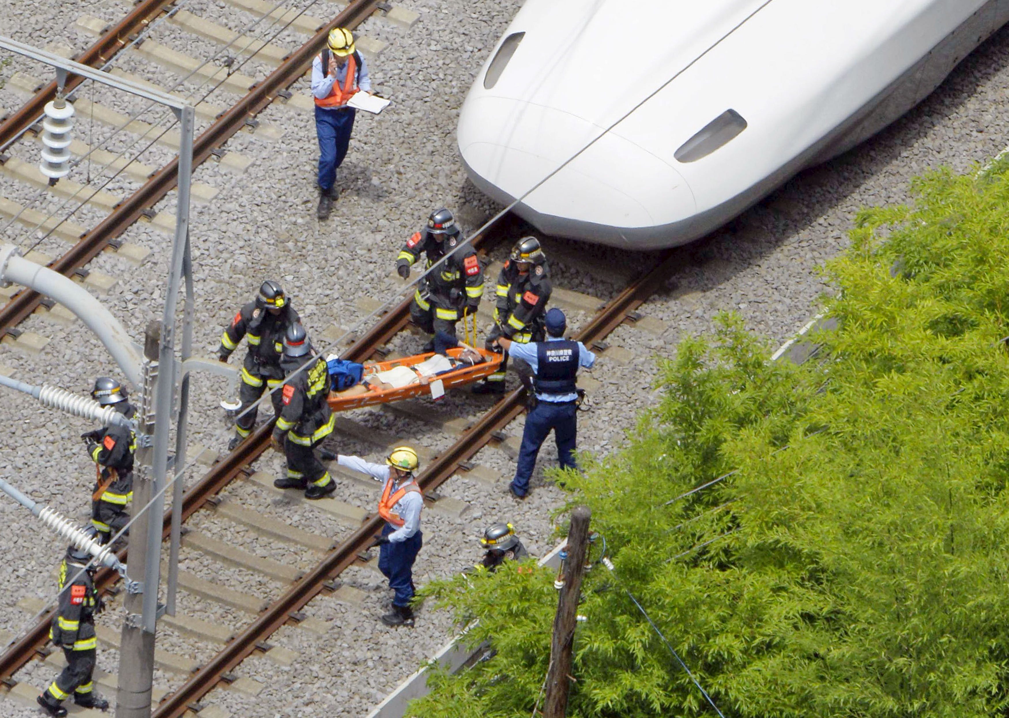 A passenger on the stretcher is carried by rescue workers from a Shinkansen bullet train after it made an emergency stop in Odawara