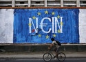 Man cycles by fresh anti-EU graffiti in Athens, Greece