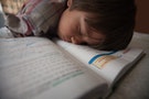 Boy sleeping on open textbook.