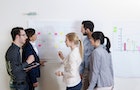 Group of young business people and businesswoman in discussion in office, using whiteboard, Germany