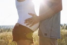 Cropped shot of young man touching pregnant girlfriends stomach in field