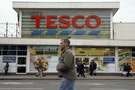Pedestrians pass a Tesco supermarket in London