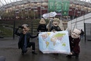 Protesters wearing masks of world leaders hold a map and a sign on the last day of U.N. climate talks in Warsaw