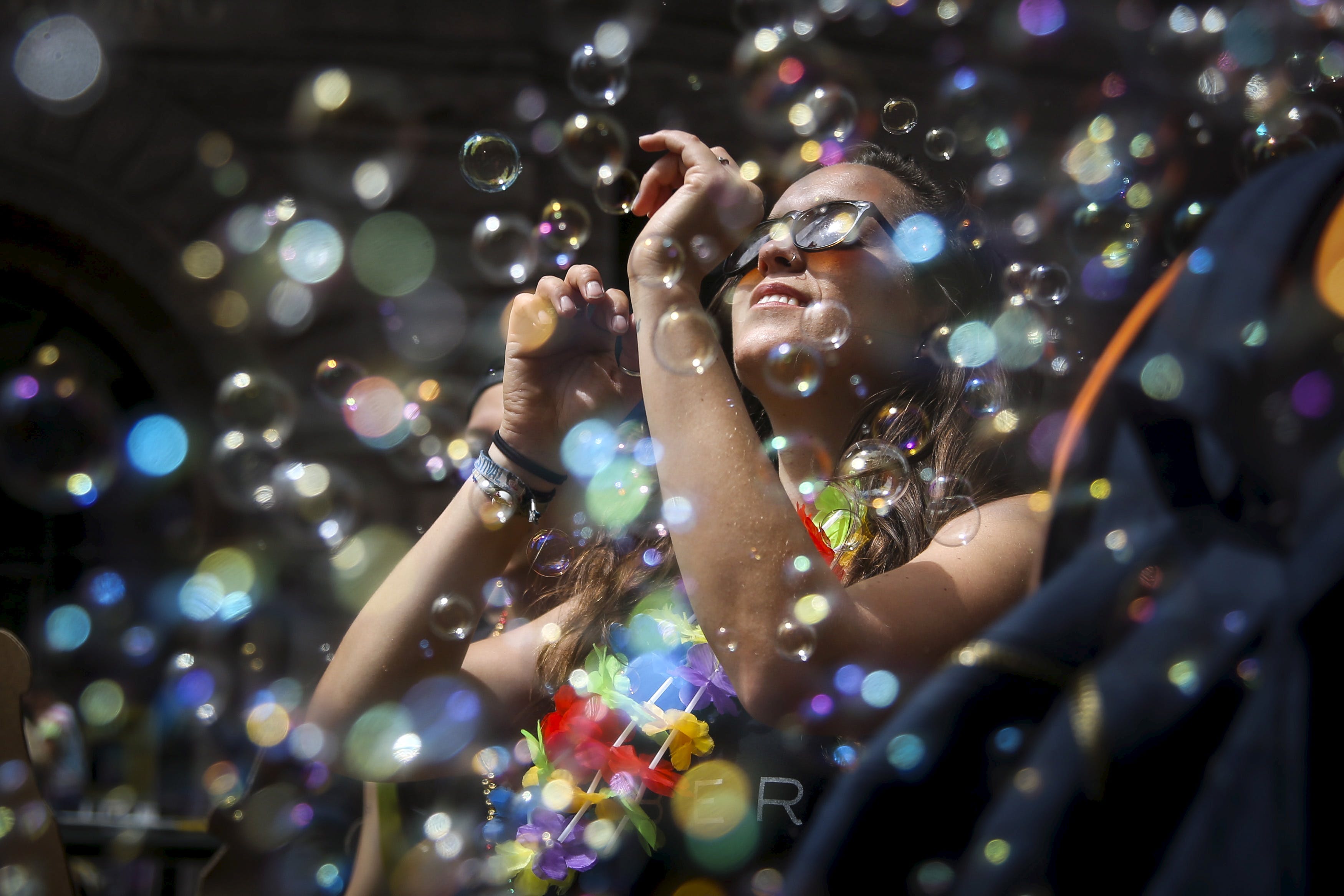 A woman dances in a cloud of bubbles while marching in a gay pride parade in San Francisco, California