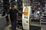 A man demonstrates the use of a Bitcoin ATM at a bookstore in Acharnai in northern Athens, Greece