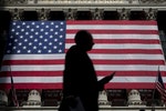 A morning commuter passes by the U.S. flag hung on the facade of New York Stock Exchange