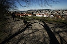 A woman walks with a dog on a hill near the city of St. Gallen in St. Gallen