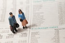 Toy Figures of a Man and Woman Stood on a Page of a Financial Newspaper