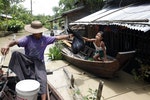 一位女孩在半淹沒的房子拿取救濟物品，地點是在伊洛瓦底三角洲，截至8月5日，已有26萬人受到緬甸水災的影響。