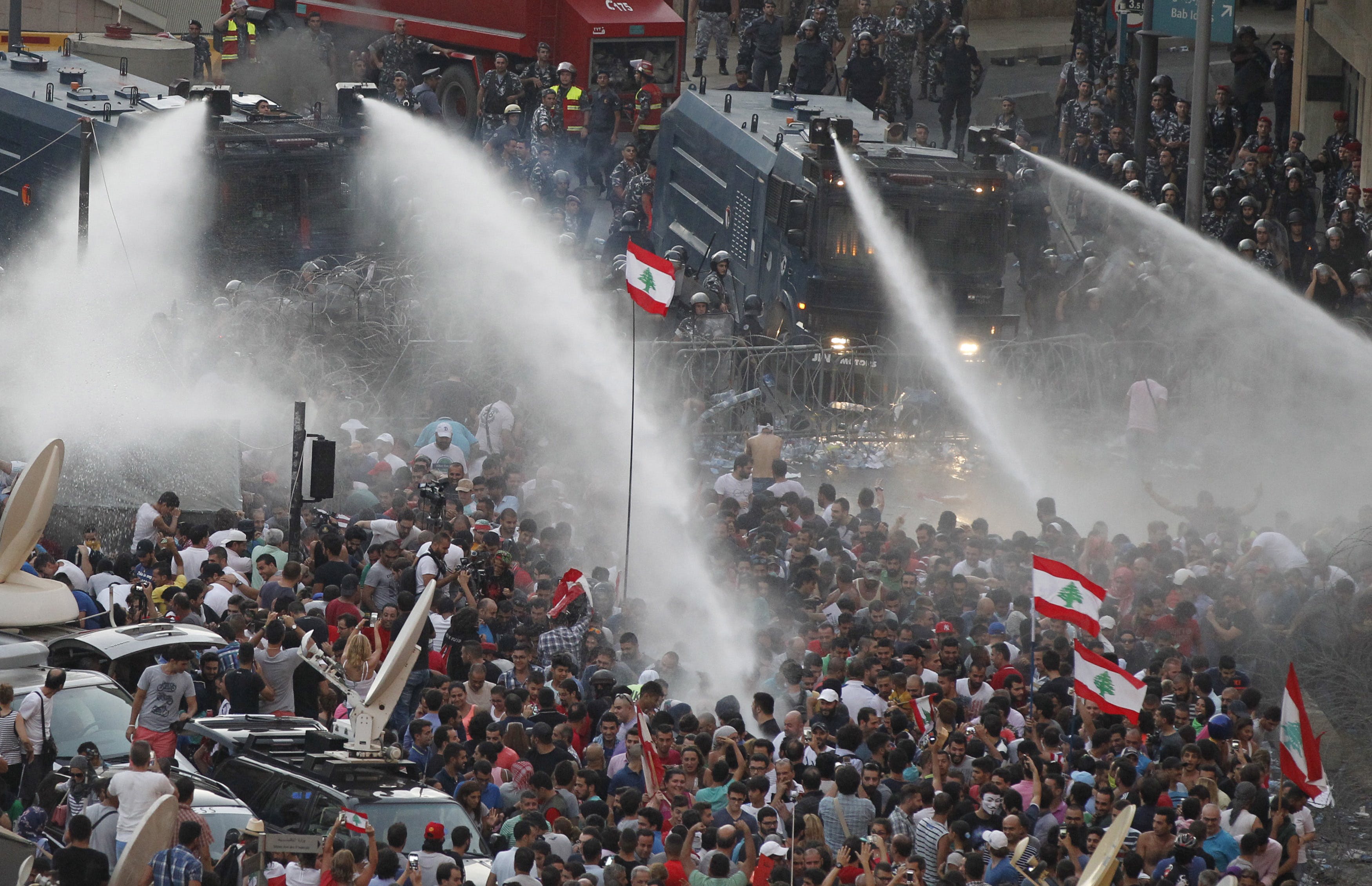 Lebanese protesters are sprayed with water during a protest against corruption and against the government's failure to resolve a crisis over rubbish disposal, near the government palace in Beirut, Leb