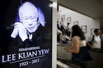 Commuters pass by a signboard displaying a tribute to the late first prime minister Lee Kuan Yew in a train station at the central business district in Singapore