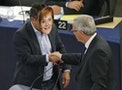 Italian Member of the European Parliament Buonanno wears a mask depicting German Chancellor Merkel as he shakes hands with European Commission President Juncker during his address to the European Parl