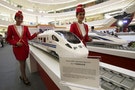 Attendants pose for a photo beside the models of a high speed train during the China High Speed Railway on Fast Track exhibition in Jakarta
