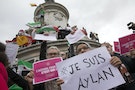 People hold signs during a demonstration asking for a change in the refugee policy in Europe on the Republique square in Paris