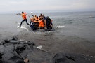 A Syrian refugee jumps off an overcrowded dinghy upon arriving on the Greek island of Lesbos after crossing a part of the Aegean Sea from the Turkish coast