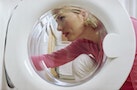 Woman crouching behind door of washing mashine