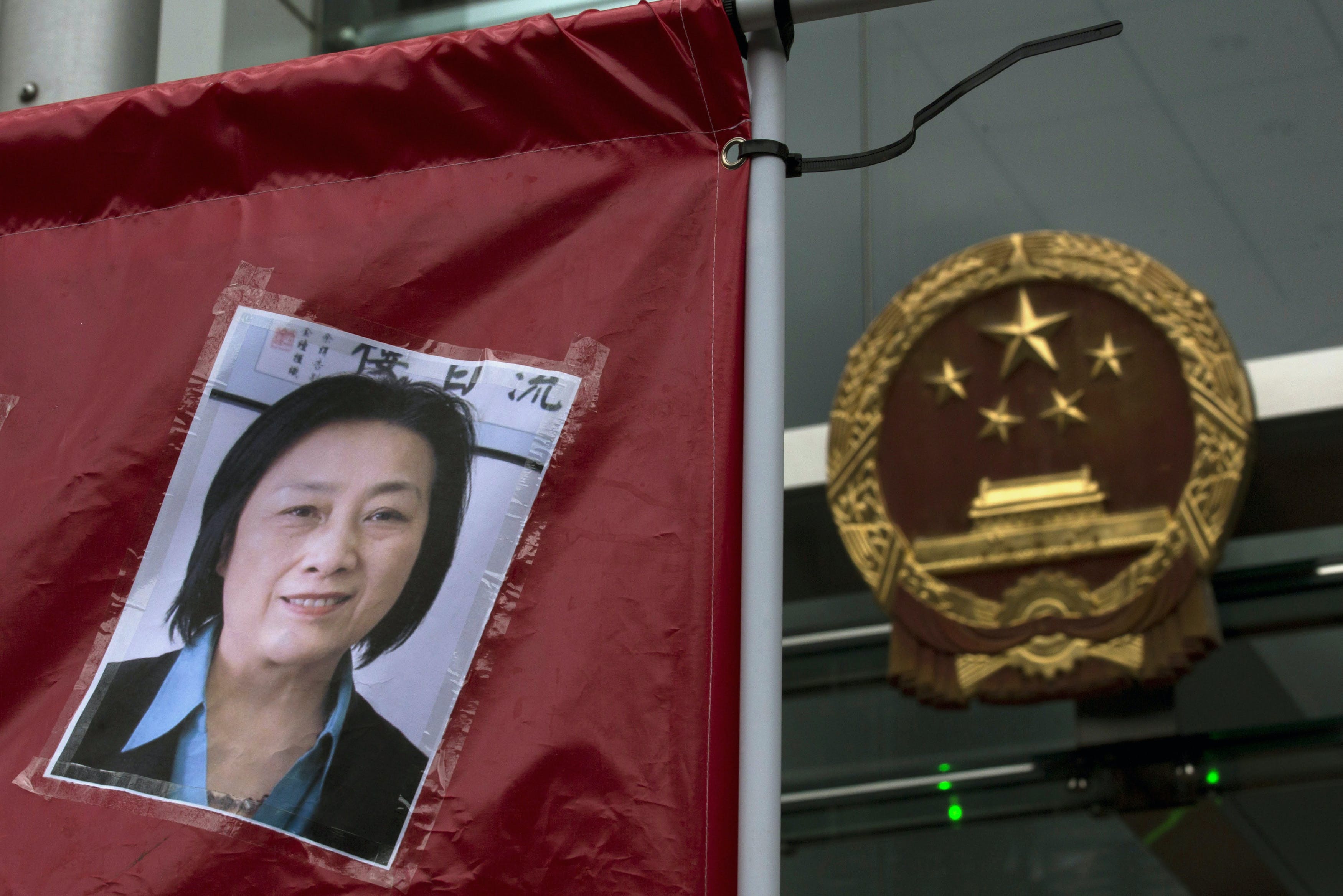 A portrait of Chinese journalist Gao Yu is displayed by a protester in front of the national emblem of China during a demonstration outside the Chinese liaison office in Hong Kong