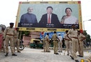 Police personnel stand guard in front of a boarding with images of India's PM Modi, China's President Xi and Patel, Chief Minister of Gujarat, ahead of Xi's arrival in Ahmedabad