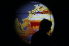 A woman walks past a map showing the elevation of the sea in the last 22 years during the World Climate Change Conference 2015 at Le Bourget