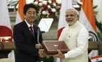 Japan's PM Abe and his Indian counterpart Modi shake hands while exchanging documents during a signing of agreement at Hyderabad House in New Delhi