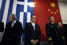 Greek PM Tsipras smiles in front of a Greek national flag and a Chinese national flag before his speech aboard the Chinese frigate Changbaishan at the port of Piraeus, near Athens