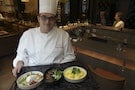 Chef Thomas Bruno holds a tray with "steamed cod with seasonal vegetables cooked in olive oil and lemon", "Caramelized potatoes stuffed with pork meatloaf" and "Old style eggs" in AccorHotels' Sofitel