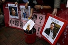 A pro-democracy demonstrator burns a letter next to pictures of missing staff members of a publishing house and a bookstore during a protest to call for an investigation behind their disappearance, ou