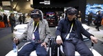 Attendees sit in a virtual reality simulator as they watch a VR movie featuring an autonomous Kia Soul at the Kia booth during the 2016 CES trade show in Las Vegas