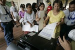 Filipinos wait in line to scan their ballots inside a counting machine at a voting center in San Juan, east of Manila, Philippines on Monday May 10, 2010. About 50 million Filipinos will vote Monday to elect a new president, vice-president and officials to fill nearly 18,000 national and local post in the country's first ever automated elections. (AP Photo/Aaron Favila)