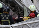 Rescue personnel help a victim at the site where a 17-storey apartment building collapsed, after an earthquake in Tainan