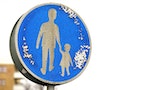 Close-up of a signpost indicating to take care of kids while crossing the road