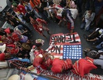 Protesters, some of whom are indigenous peoples known as "Lumad" dance as they stomp on a mock U.S. flag during a rally Monday, Nov. 24, 2014 at the U.S. Embassy in Manila to protest the presence of U.S. troops in southern Philippines under the "Visiting Forces Agreement" entered into by the Philippines. The protesters embarked on a caravan from their communities in southern Philippines 13 days ago and are set to camp out in Manila until Dec.10 for the observance of UN Declaration of Human Rights. (AP Photo/Bullit Marquez)