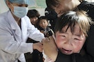 A girl cries in her mother's arm while receiving a vaccination from a nurse at a hospital in Huaibei
