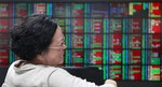 A woman laughs while monitoring stock market prices inside a brokerage in Taipei, Taiwan