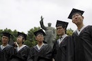 Graduates pose for pictures in front of a statue of late Chinese leader Mao Zedong at a university in Shanghai