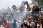 A man plays a trumpet while people are splashed by elephants with water during the celebration of the Songkran water festival in Thailand's Ayutthaya province, north of Bangkok, April 11, 2016. REUTERS/Jorge Silva TPX IMAGES OF THE DAY - RTX29E5Y