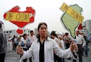 A woman holds cutouts of maps of China and Taiwan during a huge protest of around 20,000 demonstrato..