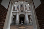 A woman walks past the Edwardian Baroque-style main building, the oldest structure on the University of Hong Kong main campus opened in 1912, in Hong Kong