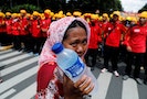A street vendor holds drinking water as she walks near workers attending a May Day rally in front of presidential palace in Jakarta