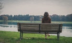 Beautiful young woman with long hair sitting on a bench in a city park