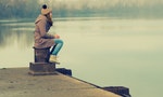 Lonely teenage girl sitting on the dock on cold winter day.