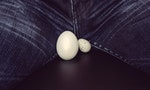 two eggs of different sizes between the legs of men. White eggs - a symbol of man's balls
