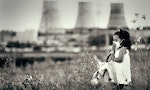 Innocent child in a respiratory mask with a doll in her hands walking against power station polluting air. Ecological theme.