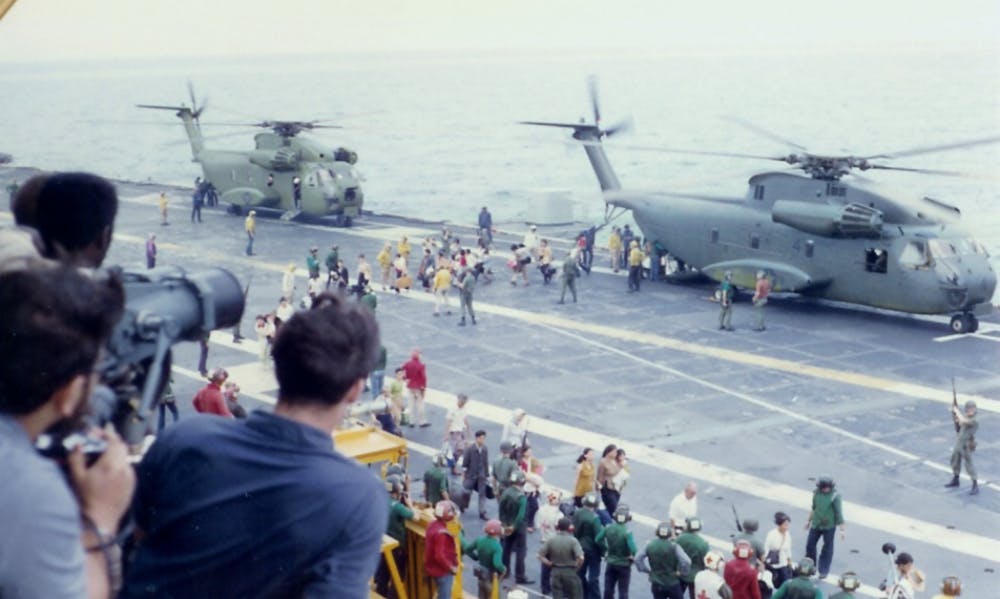 Refugees from South Vietnam debark U.S. Marine Corps Sikorsky CH-53 Sea Stallion helicopters on the flight deck of the U.S. Navy aircraft carrier USS Hancock (CVA-19) during Operation Frequent Wind, b