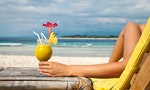 Woman holding a fruit cocktail on a tropical beach