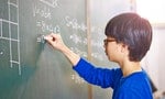 asian grade school student solving a geometry problem on chalkboard in math class.